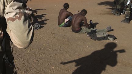 Un soldat malien surveille deux combattants soup&ccedil;onn&eacute;s d'appartenir au Mujao, le 22 f&eacute;vrier 2013 &agrave; Gao, au&nbsp;Mali. (JOEL SAGET / AFP)