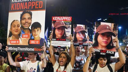 Des manifestants tenant des portraits d'otages du Hamas, dont ceux de la famille Kalderon (à gauche), le 11 novembre 2023. Les deux adolescents Sahar et Erez ont été libérés le 27 novembre 2023. (AHMAD GHARABLI / AFP)