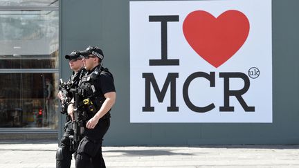 Des policiers passent devant une affiche "J'aime Manchester", le 27 mai 2017. (OLI SCARFF / AFP)