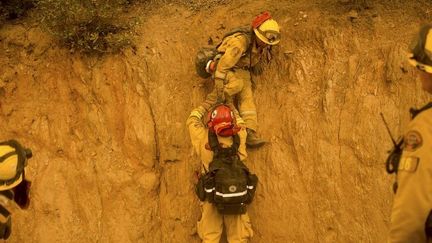 Les pompiers se font la courte &eacute;chelle pour gravir ce talus escarp&eacute; et combattre le feu pr&egrave;s de San Andreas en Californie, le 12 septembre 2015. (NOAH BERGER / REUTERS)