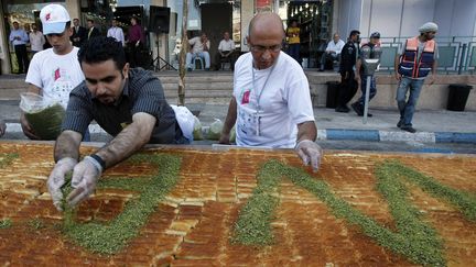 Des Palestiniens confectionnent le plus grand knafeh au monde en juillet 2009 (JAAFAR ASHTIYEH / AFP)