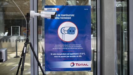 Une affiche informant de la présence d'une caméra thermique à l'entrée d'un bâtiment privé dans le quartier de la Défense, près de Paris, le 7 mai 2020. (YANN CASTANIER / HANS LUCAS / AFP)