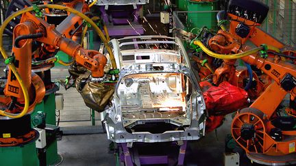 Des robots soudent des &eacute;l&eacute;ments d'une carrosserie sur une ligne d'assemblage, le 3 septembre 2004 dans l'usine Renault de Douai (Nord).&nbsp; (PHILIPPE HUGUEN / AFP)