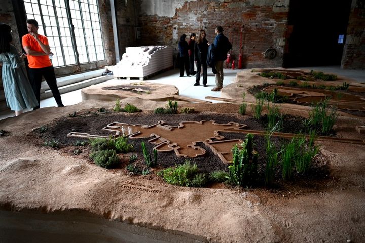 Un visiteur consulte l'installation "Sweating Assets, on climate conditioning & ecology" exposée dans le pavillon de Bahreïn, lors de la 18e Biennale internationale d'architecture de Venise le 17 mai 2023 (VINCENZO PINTO / AFP)