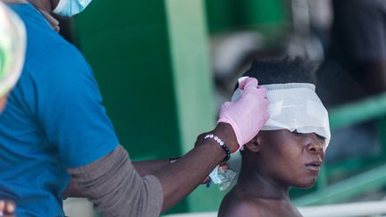 Un soignant panse la tête d'un blessé à l'hôpital des Cayes,&nbsp;situé tout près de l'épicentre du séisme qui a frappé&nbsp;Haïti dans la nuit de samedi 14 au dimanche 15 août. (REGINALD LOUISSAINT JR / AFP)