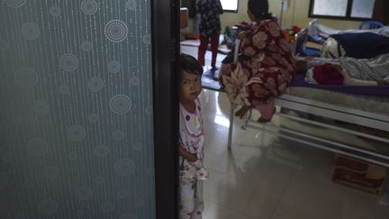 Une petite fille dans l'embrasure d'une porte, après le tsunami&nbsp;en Indonésie, le 25 décembre 2018. (MOHD RASFAN / AFP)