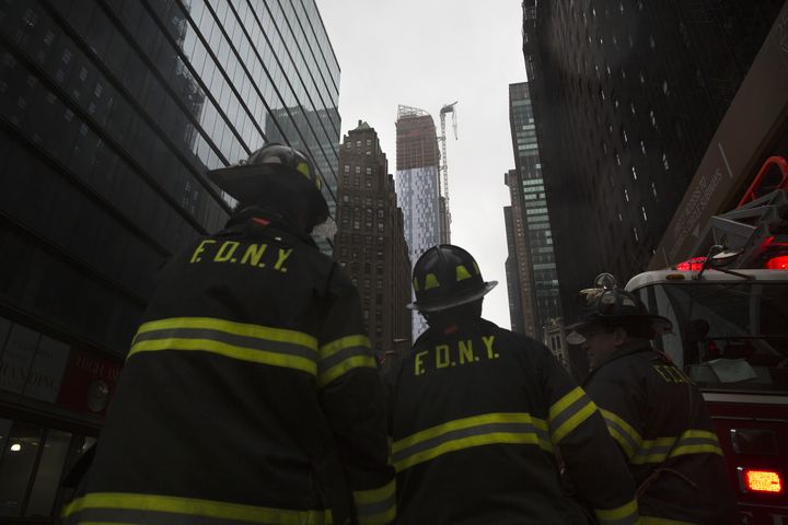 Des pompiers new-yorkais observent une grue&nbsp;partiellement arrach&eacute;e par le vent, au sommet d'un building, alors que l'ouragan Sandy s'approche de la ville, le 29 octobre 2012.&nbsp; (ANDREW KELLY / REUTERS )