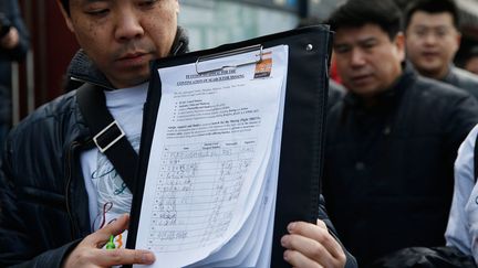 &nbsp; (La liste des passagers du MH370 présenté par un parent d'une victime chinoise © REUTERS | Kim Kyung Hoon)