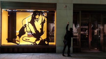 Une personne, membre&nbsp;d'Extinction Rebellion, en train d'éteindre les lumières d'une vitrine à Paris.&nbsp; (BENJAMIN ILLY / RADIO FRANCE)