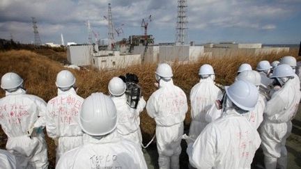 Des journalistes escortés par des employés de Tepco sur le site de Fukushima. (ISSEI KATO / POOL / AFP)