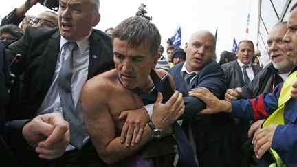 Xavier Broseta, le DRH d'Air France, est évacué par des vigiles après avoir été agressé, le 5 octobre 2015 à Roissy (Val-d'Oise), au siège d'Air France. (JACKY NAEGELEN / REUTERS)