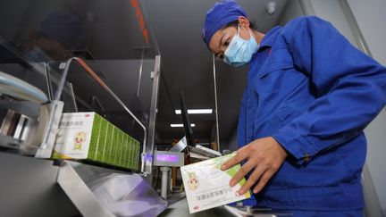 Un salarié vérifie une boîte de médicaments contre la fièvre, le 24 décembre 2022, dans une usine à Anshun (Chine). (QU HONGLUN / CNSPHOTO / AFP)