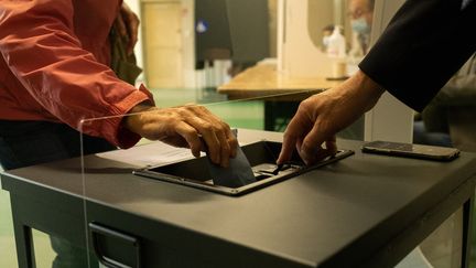 Une personne glisse son enveloppe dans l'urne pour les élections régionales et départementales à Dinan en Bretagne le 20 juin 2021. (MARTIN BERTRAND / HANS LUCAS)