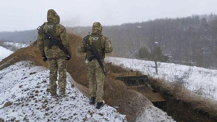 Sur cette photo fournie par le service de communication de l'armée ukrainienne, deux soldat regardent la construction d'une tranchée à la frontière russo-ukrainienne, le 21 décembre 2021. (UKRAINIAN BOARD GUARD PRESS OFFICE / AP)