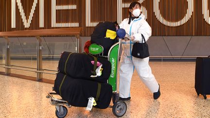 Des voyageurs avec un équipement de protection arrivent à l'aéroport de Melbourne (Australie) le 29 novembre 2021. (WILLIAM WEST / AFP)