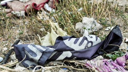 Une bannière appartenant aux jihadistes du groupe terroriste Etat islamique abandonnée à Baghouz, en Syrie, en mars 2019. (GIUSEPPE CACACE / AFP)