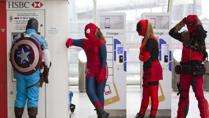 Un homme d&eacute;guis&eacute; en Captain America (G) retire de l'argent &agrave; un distributeur automatique alors que Londres (Royaume-Uni) accueille la Super Comic Convention, le 15 mars 2015. (JUSTIN TALLIS / AFP)