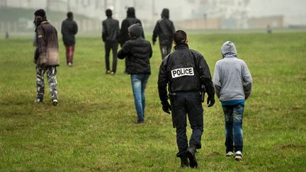 La police tente d'emp&ecirc;cher des migrants d'acc&eacute;der aux camions &agrave; destination de la Grande-Bretagne, en octobre 2014 &agrave; Calais. (PHILIPPE HUGUEN / AFP)