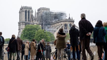 Des badauds observent Notre-Dame de Paris, le 16 avril 2019.&nbsp; (MARCEL KUSCH / DPA / AFP)