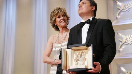 Le réalisateur roumain, Cristian Mungiu, soulève la palme d'or, aux côtés de Jane Fonda, au festival de Cannes 2007. (TONY BARSON ARCHIVE / WIREIMAGE)