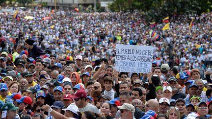 Un homme tient au milieu de la foule une pancarte "Le peuple ne devrait pas avoir peur du gouvernement mais le gouvernement devrait avoir peur du peuple", le 23 janvier, à Caracas. (FEDERICO PARRA / AFP)