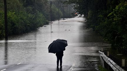 Un homme face à une route inondée dans la banlieue de Richmond (Australie), le 22 mars 2021. (SAEED KHAN / AFP)