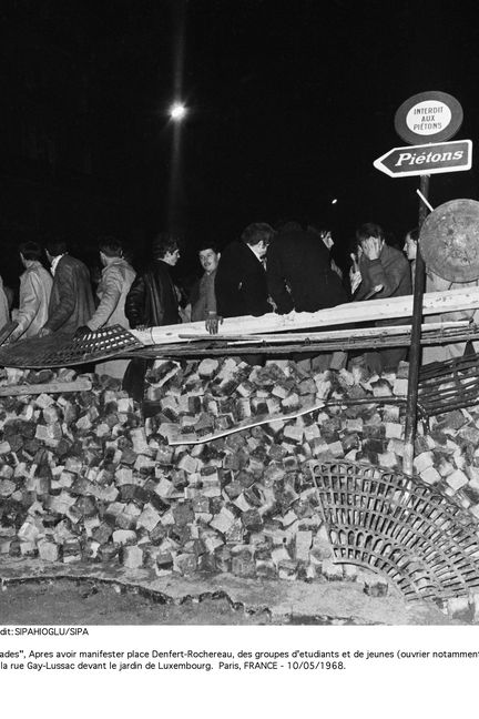 Des étudiants sur une barricade érigée&nbsp;sur le boulevard Saint-Michel, à l'intersection de la rue Gay-Lussac, devant le jardin du Luxembourg à Paris, le 10 mai 1968. (SIPAHIOGLU / SIPA)