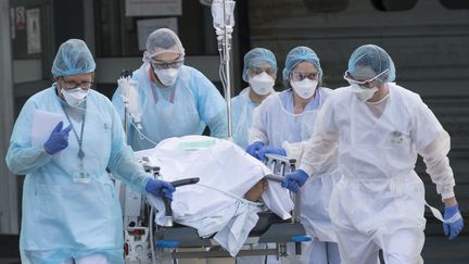 Des soignants transportent un malade du coronavirus&nbsp;à l'hôpital Emile-Muller à Mulhouse (Haut-Rhin), le 17 mars 2020.&nbsp; (SEBASTIEN BOZON / AFP)