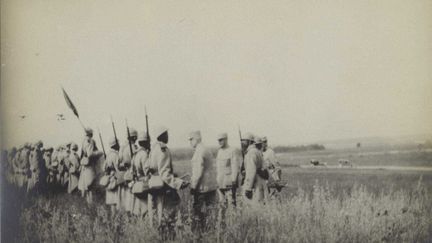 Les photos représentant militaires et travailleurs coloniaux pendant la Première guerre mondiale édulcorent les horreurs de la guerre. En général, sur ce type de documents, on trouve peu de morts, tout juste ça et là quelques cadavres. Il s’agit ainsi «de populariser (le conflit) en cours et d’en donner une représentation conforme aux nécessités de la propagande», note le site histoire-image.org. La propagande que l’on appelait alors, de manière très imagée, le «bourrage de crâne». Celle-ci entendant montrer que les hommes venus d’Afrique sont des hommes humbles et braves qui prennent leur part dans l’effort de guerre. Et sont récompensés comme il se doit par la mère patrie reconnaissante, représentée par ses plus hauts dignitaires… Ici, les généraux Philippe Pétain (devenu par la suite maréchal), le «vainqueur de Verdun», et Robert Nivelle (que l’Histoire a retenu comme l’organisateur de la très sanglante et désastreuse offensive du Chemin des Dames en avril 1917) passent en revue des tirailleurs sénégalais à une date inconnue quelque part sur le front.
 (Coll. La contemporaine. Source ou opérateur : Cl. lieutenant Tardieu )