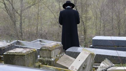 Un rabbin prie devant des tombes juives profan&eacute;es dans le cimeti&egrave;re de Sarre-Union (Bas-Rhin), le 17 f&eacute;vrier 2015. (MAXPPP)