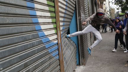 Un casseur s'attaque &agrave; une devanture de magasin en marge d'une manifestation &eacute;tudiante &agrave; Santiago (Chili), le 11 avril 2013. (IVAN ALVARADO / REUTERS)