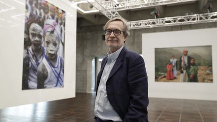 Le fondateur et président du festival Visa pour l'image de Perpignan, Jean-François Leroy est aussi le directeur artistique de L'Arche du photojournalisme à Paris. Il pose en 2017 devant le travail de l'Américaine Stéphanie Sinclair. (THOMAS SAMSON / AFP)