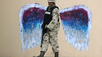 Un soldat passe devant un graffiti &agrave; Ciudad Juarez (Mexique), le 18 mars 2015. (  REUTERS)