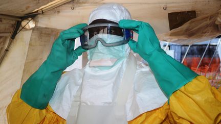 Un membre de M&eacute;decins sans Fronti&egrave;res enfilant une combinaison de protection &agrave; l'h&ocirc;pital de Conakry (Guin&eacute;e), o&ugrave; s&eacute;vit le virus Ebola depuis f&eacute;vrier 2014. (CELLOU BINANI / AFP)