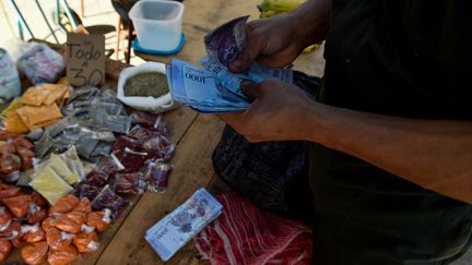 Un homme compte des billets de 1 000 bolivars, sur un marché de Caracas (Venezuela), le 20 juin 2018. (FEDERICO PARRA / AFP)