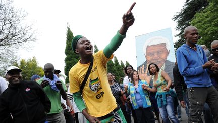 Un homme v&ecirc;tu des couleurs du parti ANC rend hommage &agrave; Nelson Mandela, devant la maison de l'ancien pr&eacute;sident sud-africain &agrave; Johannesbourg, le 6 d&eacute;cembre 2013. (STEPHANE DE SAKUTIN / AFP)