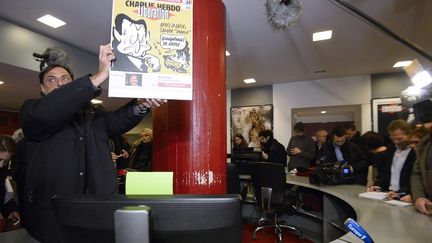 Lib&eacute;ration accueille le 9 novembre dans ses locaux l'&eacute;quipe &eacute;ditoriale de Charlie Hebdo, apr&egrave;s la tuerie du 7 novembre au journal satirique. La Une de Lib&eacute;ration brandie date de novembre 2011. (BERTRAND GUAY / AFP)