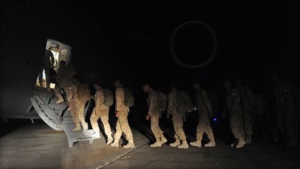 Des soldats canadiens embarquent dans un avion sur leur base de Kandahar, en Afghanistan, le 5 juillet 2011. (SHAH MARAI / AFP)