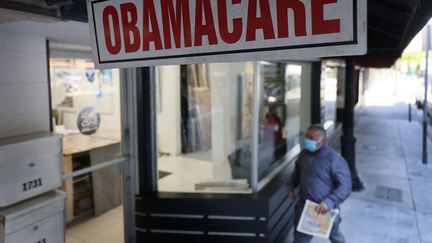 Un passant devant une agence qui propose des offres en accord avec la loi sur les soins abordables, dite "Obamacare", le 28 janvier 2021 à Miami, en Floride (Etats-Unis). (JOE RAEDLE / GETTY IMAGES NORTH AMERICA / AFP)