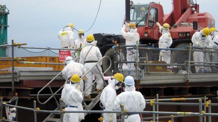 Des ouvriers de&nbsp;Tokyo Electric Power Co (TEPCO) retirent des combustibles nucl&eacute;aires de la centrale de Fukushima (Japon), le 18 juillet 2012. (TEPCO / AFP)