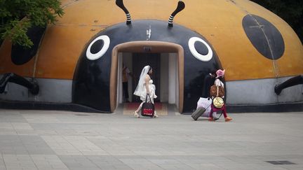 Une femme en robe de mari&eacute;e passe devant des toilettes publiques &agrave; P&eacute;kin (Chine), le 18 juin 2012. (DIEGO AZUBEL / EPA / MAXPPP)