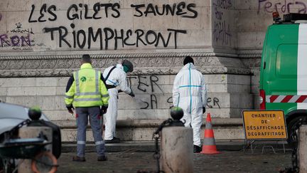 Des ouvriers nettoient les tags laissés sur l'Arc de Triomphe, à Paris, le 2 décembre 2018, au lendemain de la mobilisation des "gilets jaunes". (BENOIT TESSIER / REUTERS)