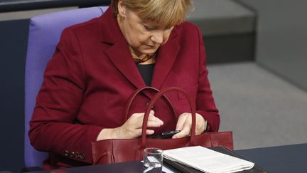 Angela Merkel consulte son téléphone au Bundestag, l'Assemblée allemande, à Berlin, le 15 octobre 2015. (HANNIBAL HANSCHKE)