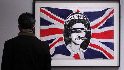 Un visiteur observe le tableau "God Save the Queen" de l'artiste Jamie Reid, créé en hommage au tube des Sex Pistols.&nbsp; (PETER MUHLY / AFP)