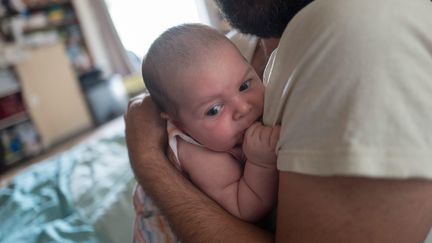 Un homme tient son bébé dans les bras. (Illustration).&nbsp; (QUEMENER YVES-MARIE / MAXPPP)