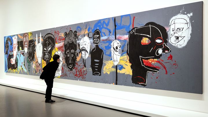 Un visiteur regarde "African Masks", une peinture acrylique réalisée à quatre mains par Basquiat et Warhol (1984-1985), à la Fondation Vuitton (Paris, France), le 29 mars 2023. (BERTRAND GUAY / AFP)