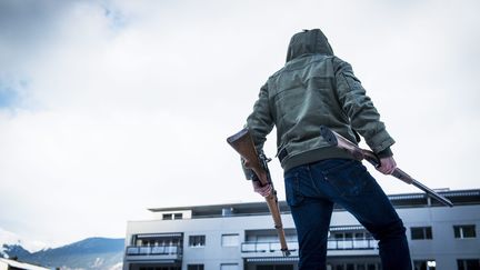 Un homme porte des fusils dans la rue, à Sion, en Suisse. (OLIVIER MAIRE / MAXPPP)