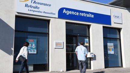 Deux personnes passent devant une agence d'assurance-retraite au Crès (Hérault), le 22 mars 2019. (PASCAL GUYOT / AFP)