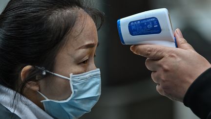 Une femme portant un masque se faisant contrôler la température à Wuhan, le 2 avril. (HECTOR RETAMAL / AFP)