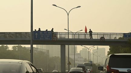 Un garde sur le pont Sitong, à Pékin (Chine), où ont été accrochées deux banderoles contre le régime, le 13 octobre 2022. (NOEL CELIS / AFP)